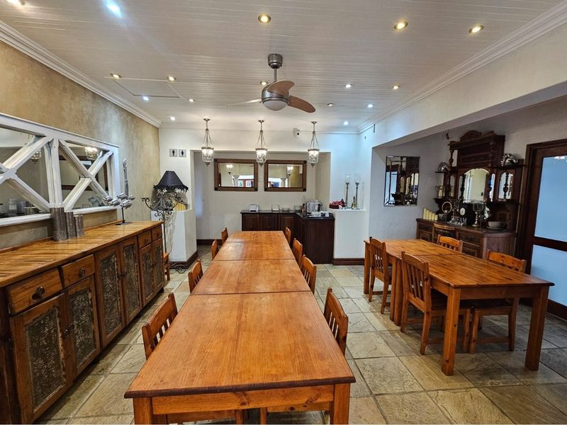 Spacious dining area featuring stone flooring, recessed ceiling lighting, a ceiling fan, and built-in cabinetry, suitable for guest house dining or events.
