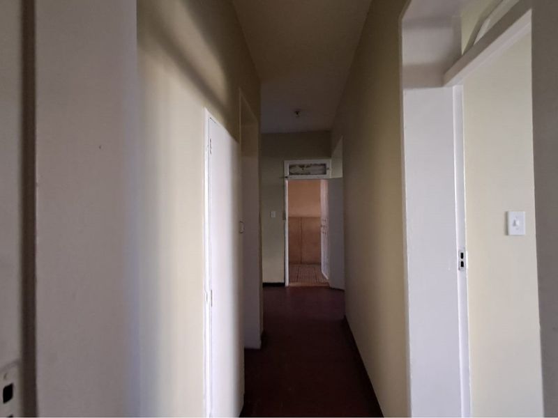 A vacant interior hallway connecting multiple rooms, featuring neutral wall finishes and standard door frames throughout the corridor.