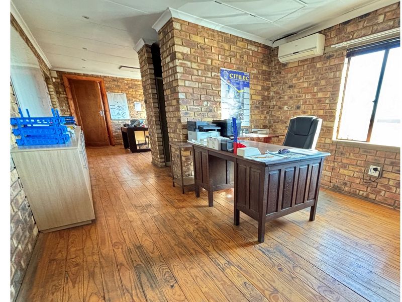 Spacious office area featuring exposed brick walls, timber flooring, and a wall-mounted air conditioning unit.