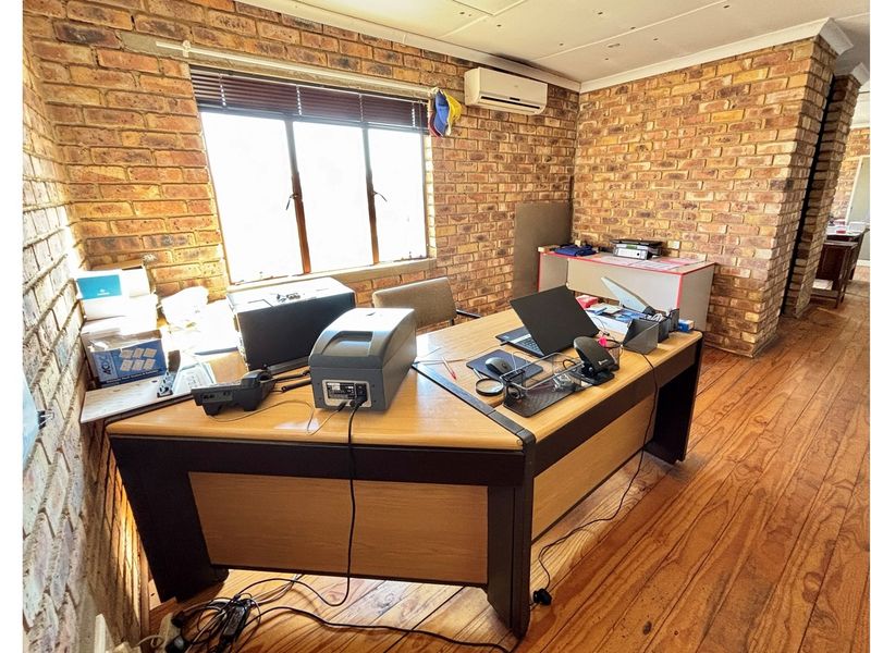 Industrial office space featuring exposed brick walls, timber flooring, and a wall-mounted air conditioning unit.