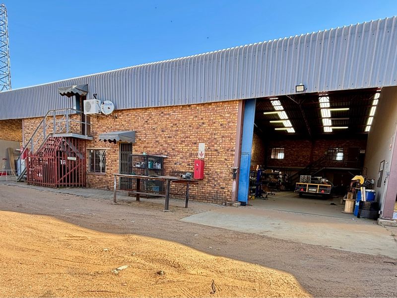 Industrial warehouse facility featuring exposed brick facade, large open-bay access, metal roofing, and external staircase access to upper levels.