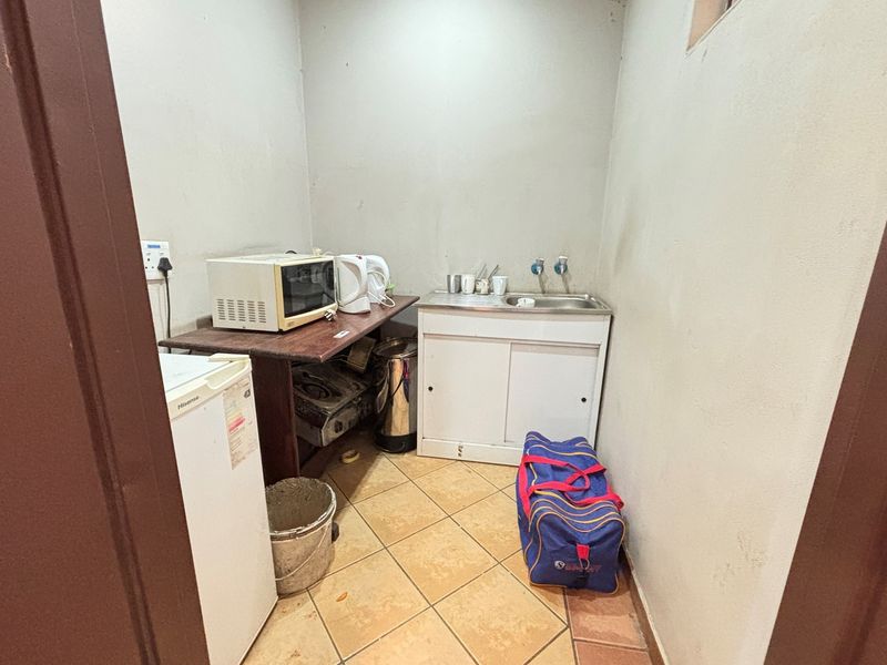 A compact utility or scullery area featuring a basic sink unit, tiled flooring, and functional wall space for food preparation or cleaning tasks.