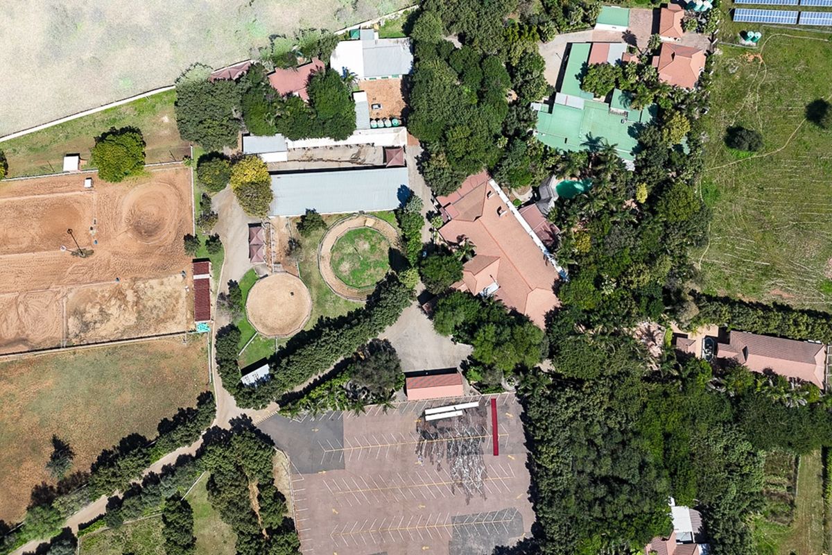 Aerial view of a large commercial property featuring extensive equestrian facilities, multiple buildings, a swimming pool, and a paved parking area.