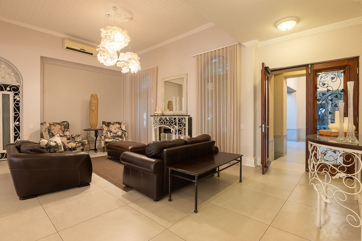 Spacious living area featuring tiled flooring, decorative ceiling paneling, a built-in fireplace, and elegant arched doorway details.