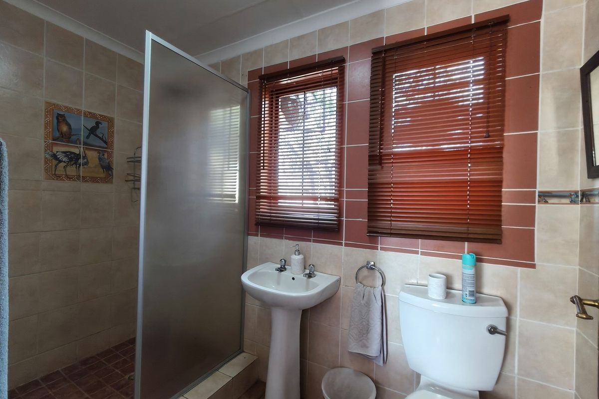 A functional bathroom featuring a pedestal basin, a toilet, and a walk-in shower enclosure with tiled walls.