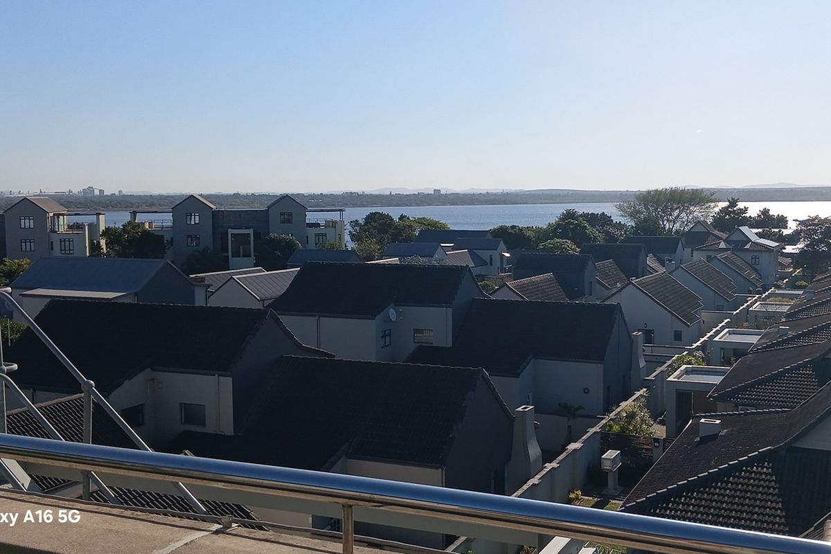 Elevated view overlooking a residential estate with a scenic water backdrop and clear horizon.