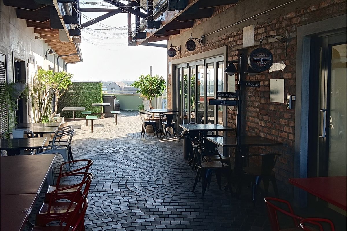 A spacious outdoor patio area featuring exposed brick walls, timber roof beams, and cobblestone flooring, providing a versatile space for office break-out or social use.