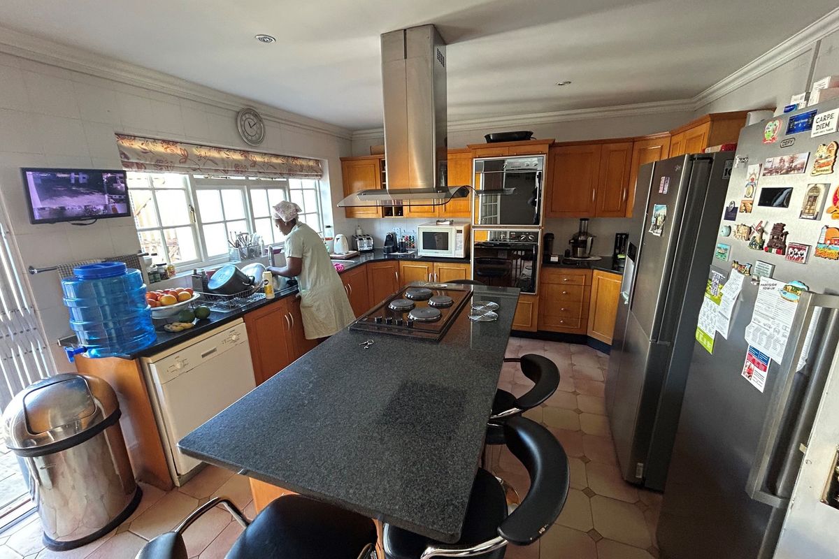 A functional kitchen featuring wooden cabinetry, a central island with a granite countertop, built-in oven, and an extractor fan.