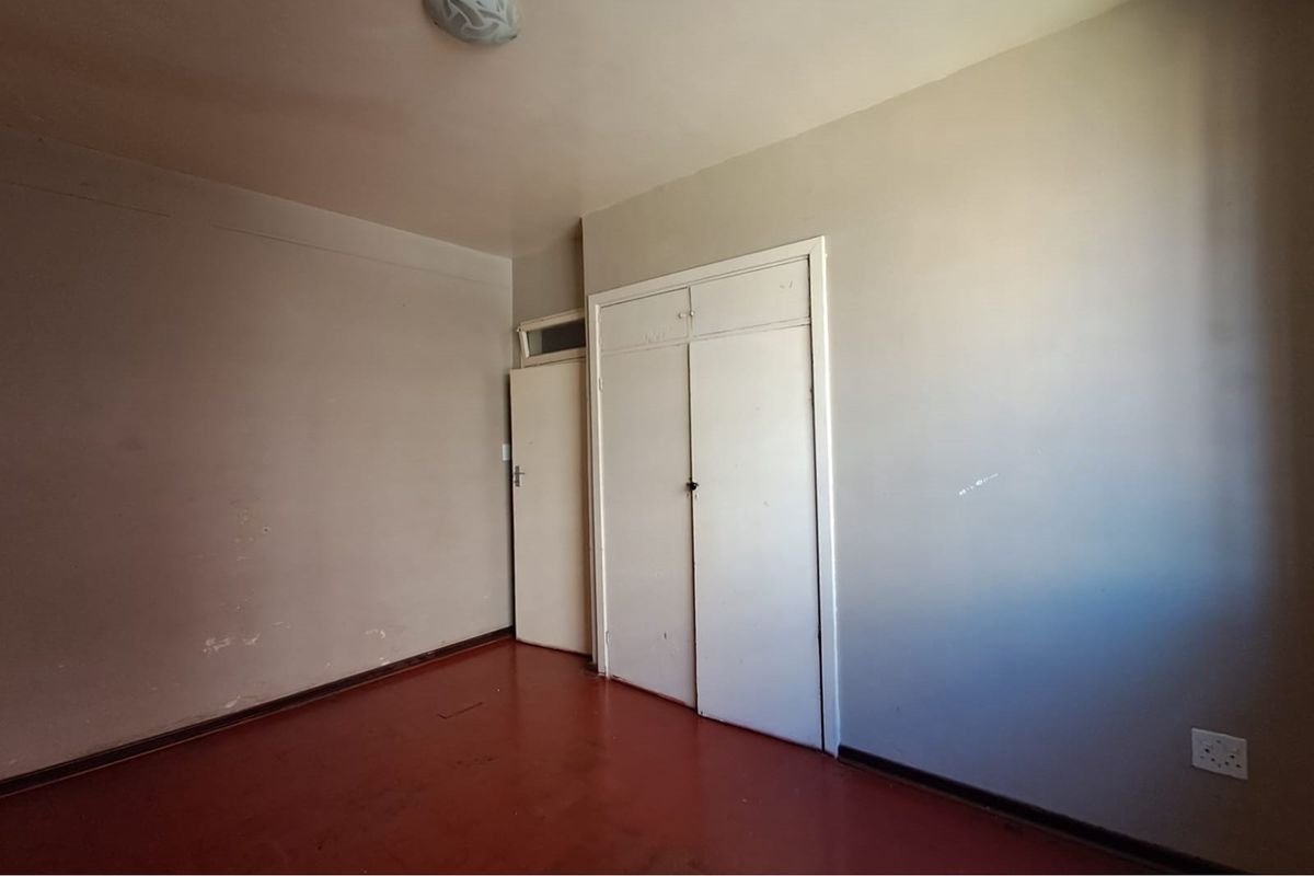 An empty bedroom featuring built-in cupboards, painted walls, and a solid floor finish, offering a blank canvas for renovation.