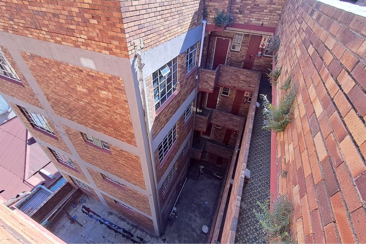 An elevated view of a multi-story brick retail or residential building showing the central courtyard, external walkways, and access doors.