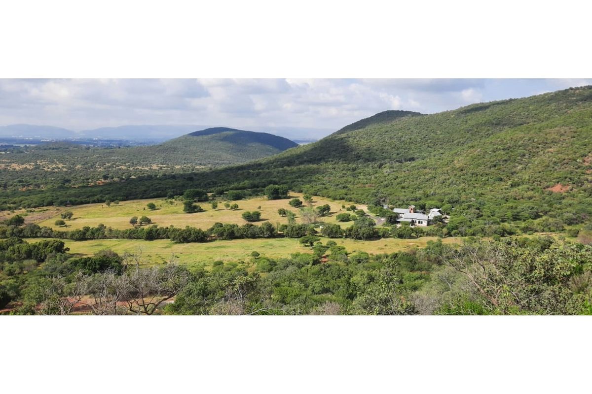 An expansive aerial view of the lodge property set within a lush, hilly landscape, showcasing the surrounding natural terrain and estate grounds.
