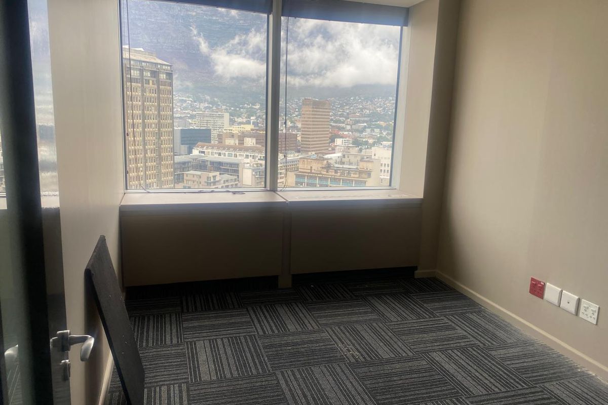 A vacant office space featuring carpet tiles, electrical and data connectivity, and large windows offering expansive city and mountain views.