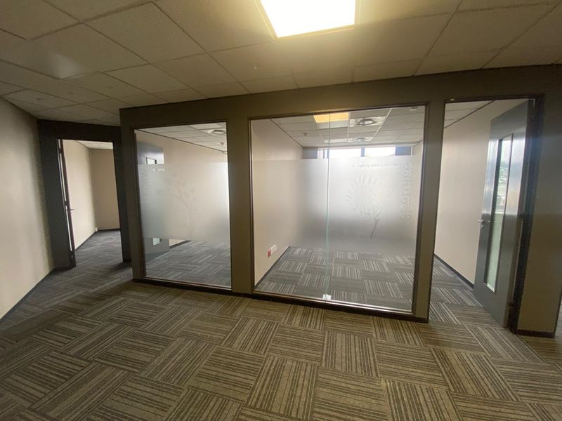 Modern office space featuring glass partition walls, suspended ceilings, and durable carpet tiles, providing a professional and flexible work environment.
