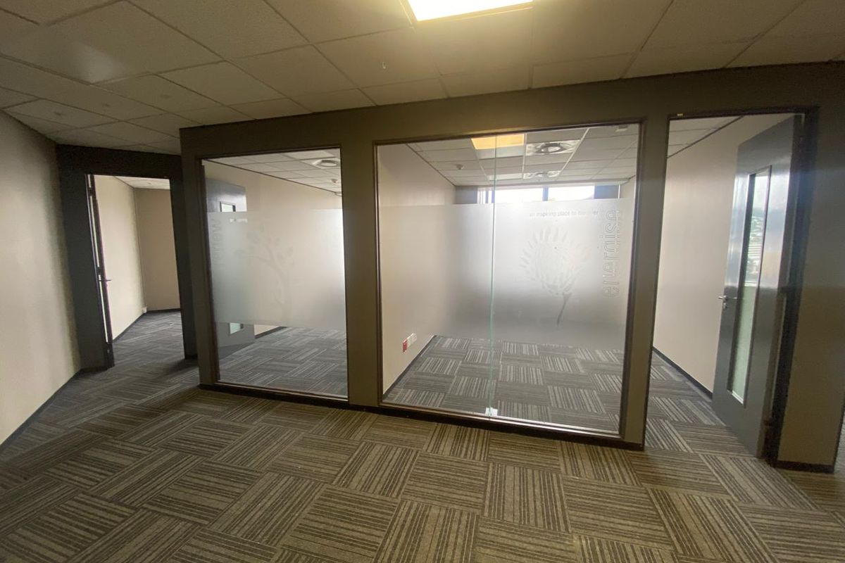 Modern office space featuring glass partition walls, suspended ceilings, and durable carpet tiles, providing a professional and flexible work environment.