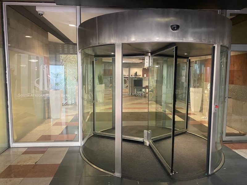 Main entrance featuring a modern revolving glass door and secure access point with tiled flooring and glass facade.