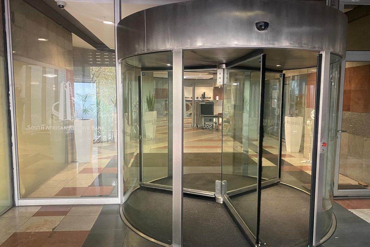 Main entrance featuring a modern revolving glass door and secure access point with tiled flooring and glass facade.