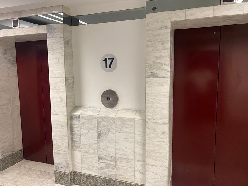 A commercial office elevator lobby on the 17th floor featuring marble wall cladding and dual elevator access.