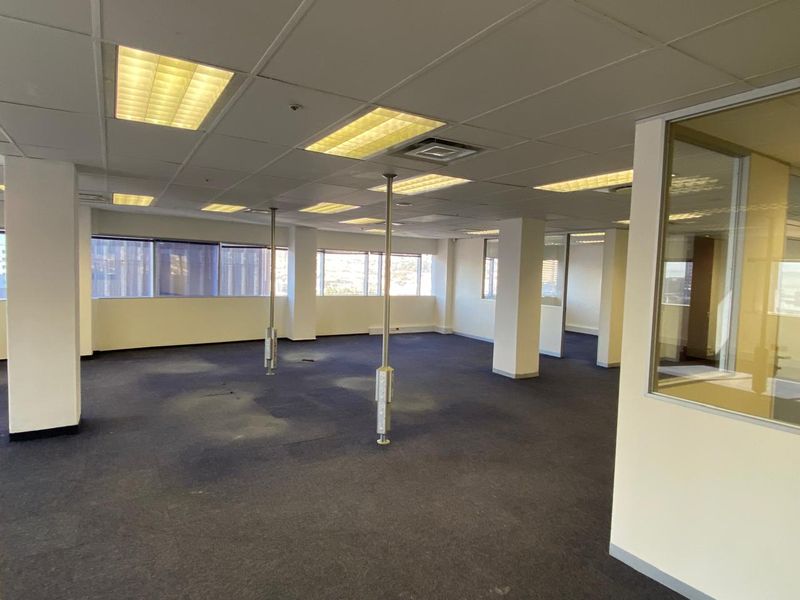 An expansive, vacant open-plan office space featuring suspended ceilings, recessed lighting, carpeted flooring, and glass partitioning, ready for custom fit-out.