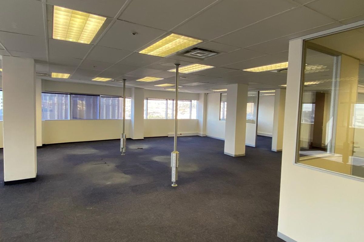 An expansive, vacant open-plan office space featuring suspended ceilings, recessed lighting, carpeted flooring, and glass partitioning, ready for custom fit-out.