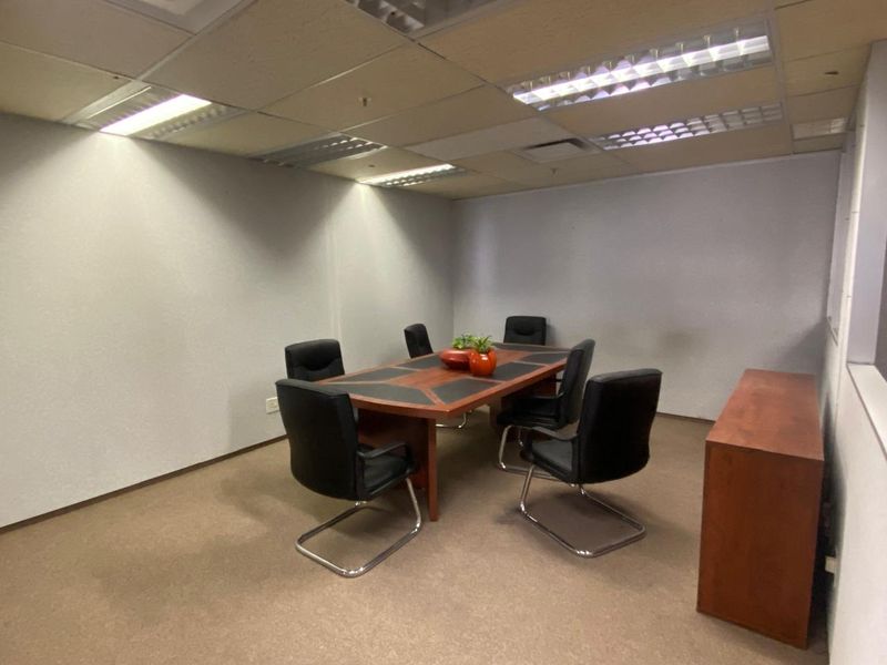 A functional office meeting room featuring a suspended ceiling with recessed lighting and carpeted flooring.