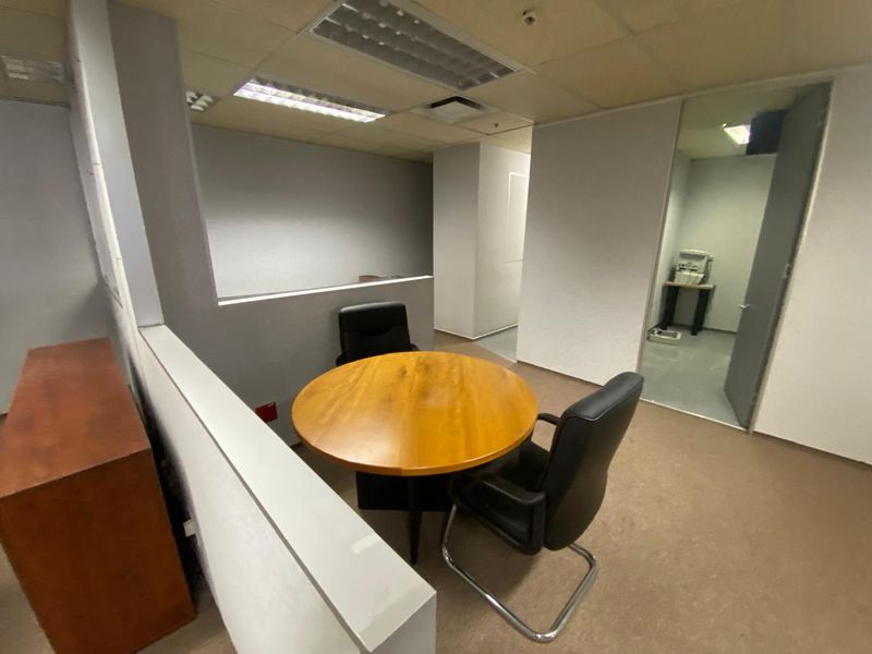 A functional office space featuring a partition wall, suspended ceiling with recessed lighting, and carpeted flooring, providing a practical layout for professional use.