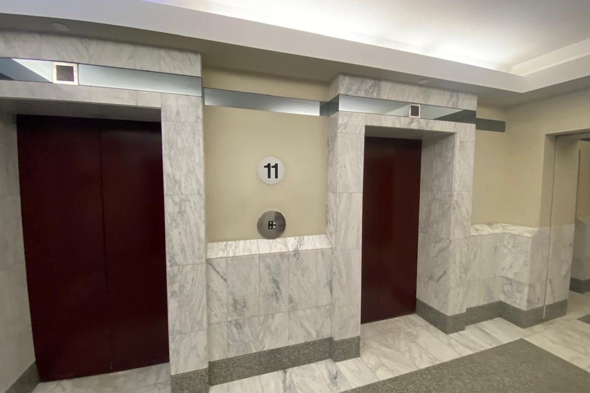 A well-maintained office building elevator lobby featuring marble wall cladding, marble flooring, and dual elevator access on the eleventh floor.