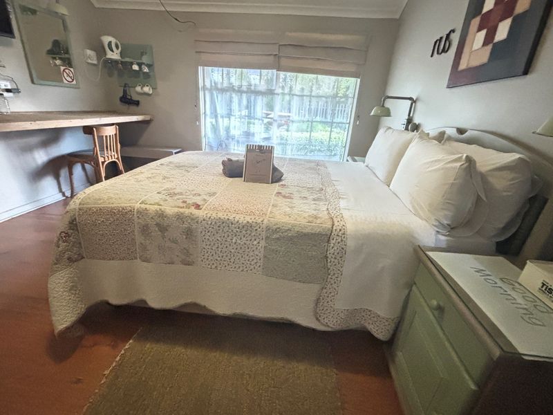 A guest bedroom featuring a built-in desk, sliding glass door with garden access, and neutral wall finishes.