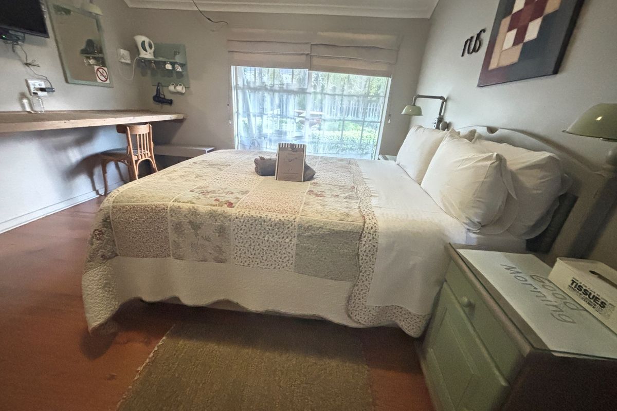 A guest bedroom featuring a built-in desk, sliding glass door with garden access, and neutral wall finishes.