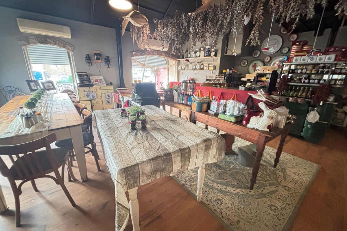 A rustic open-plan dining and retail area featuring exposed timber flooring, high ceilings, and integrated service counters within a guest house setting.