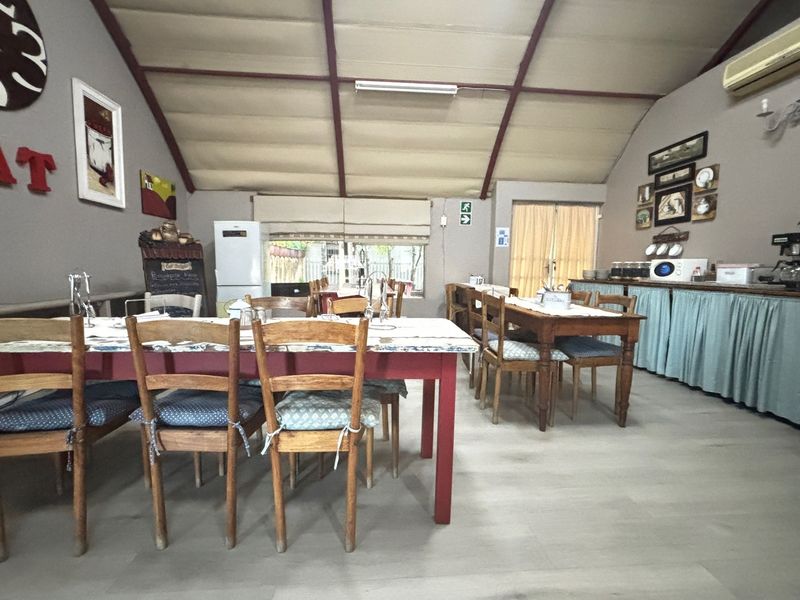 A spacious dining area featuring a vaulted ceiling, light-toned flooring, and a built-in serving counter with cabinetry.