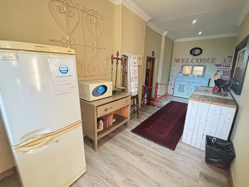 A functional hallway area featuring wood-look laminate flooring, crown molding, and a dedicated space for guest amenities.