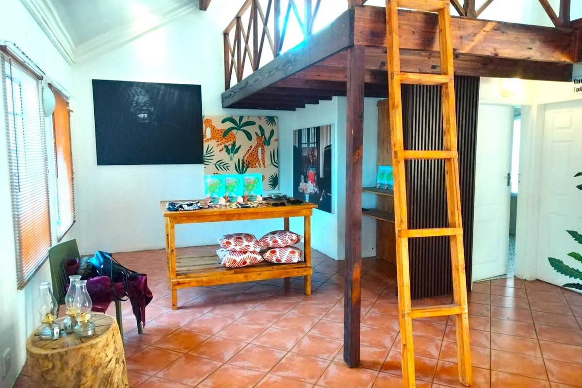 A spacious living area featuring a mezzanine level with a wooden ladder, vaulted ceilings, and terracotta floor tiles, offering a rustic and open atmosphere.