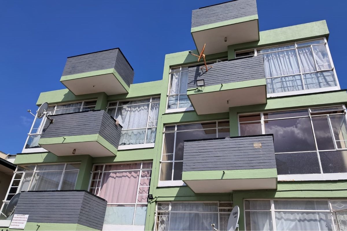 Exterior view of a multi-story retail or residential building featuring multiple balconies, large windows, and satellite dish installations.
