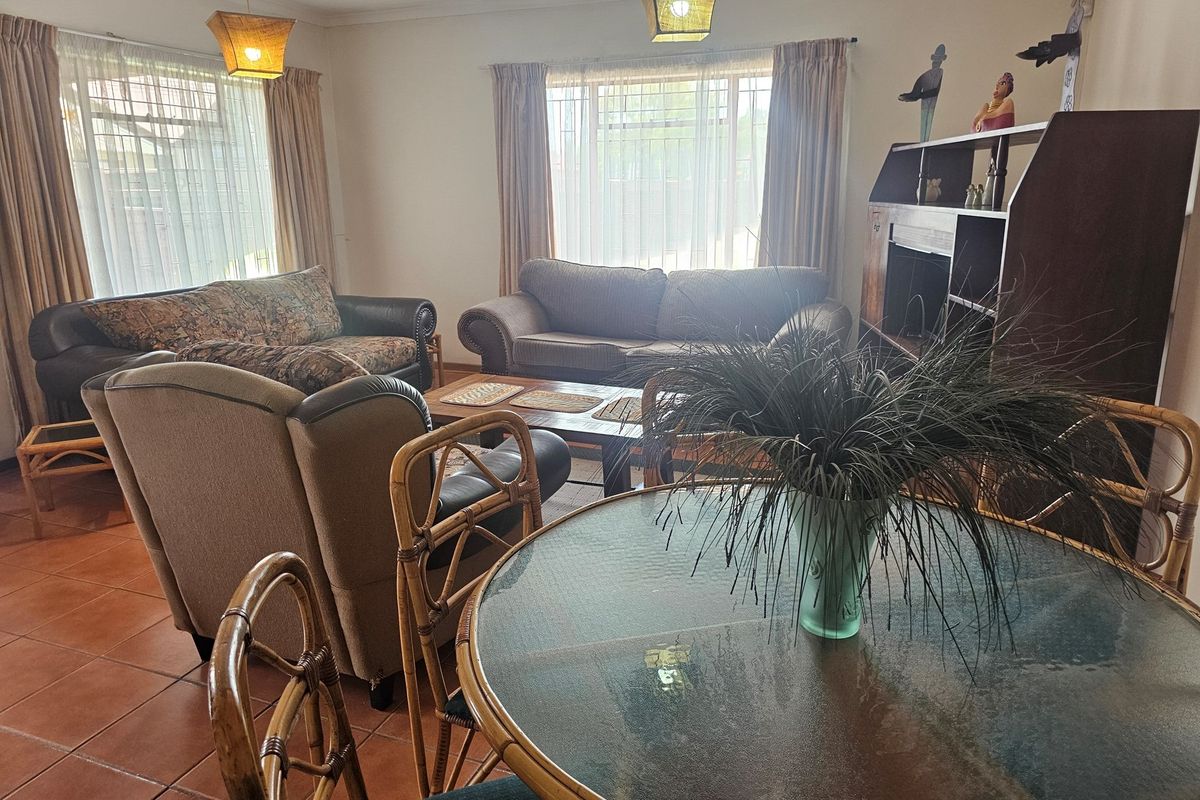 A spacious living area featuring tiled flooring and large windows that provide ample natural light, creating a comfortable and functional space.