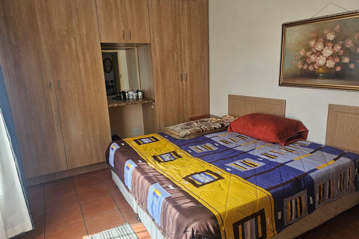 Bedroom featuring built-in wooden cabinetry with an integrated vanity area and tiled flooring.