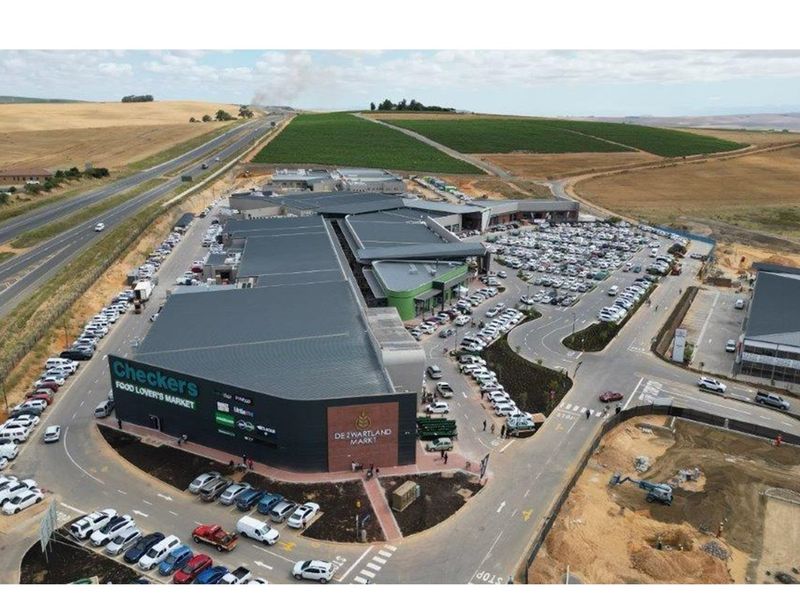 Aerial view of a modern commercial shopping center featuring extensive parking facilities, multiple retail units, and convenient access roads.