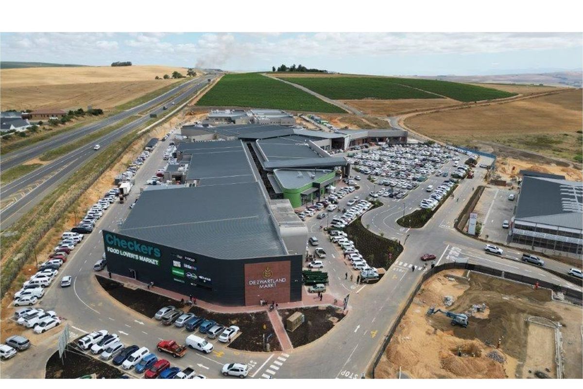 Aerial view of a modern commercial shopping center featuring extensive parking facilities, multiple retail units, and convenient access roads.
