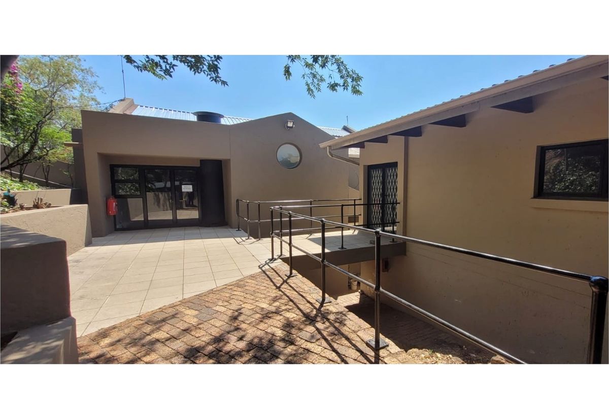 Exterior view of the office building featuring a paved courtyard, metal access ramp with railings, and modern architectural design elements.