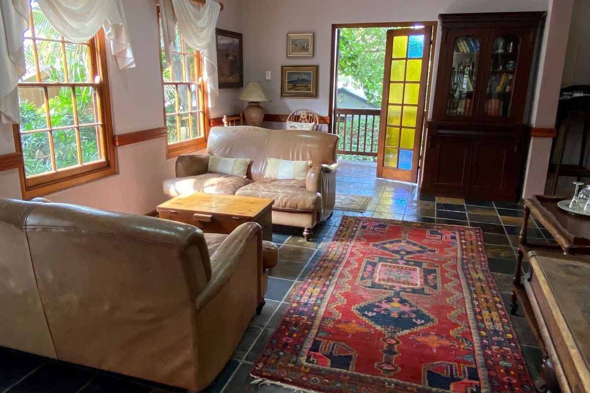 A cozy living room featuring slate tile flooring, wooden window frames, and a stained-glass door leading to an outdoor balcony area.