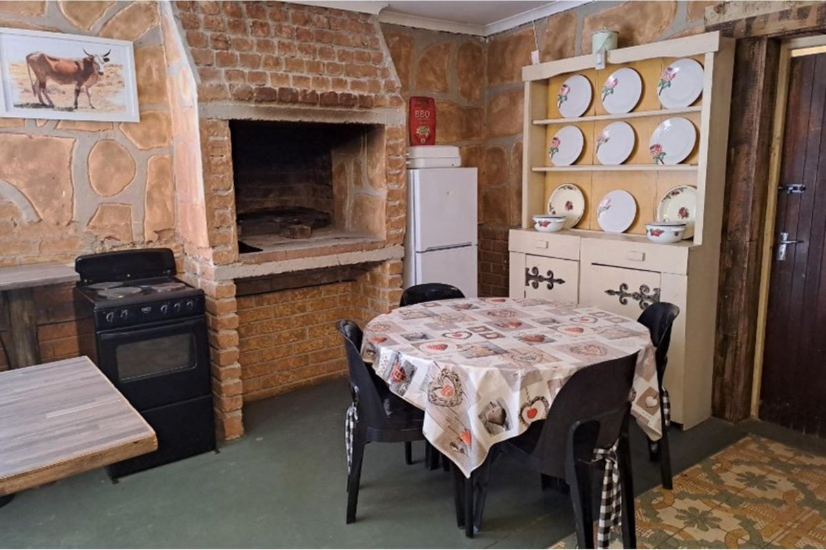 Rustic kitchen area featuring exposed brick walls, a built-in brick fireplace, and traditional stone cladding finishes.
