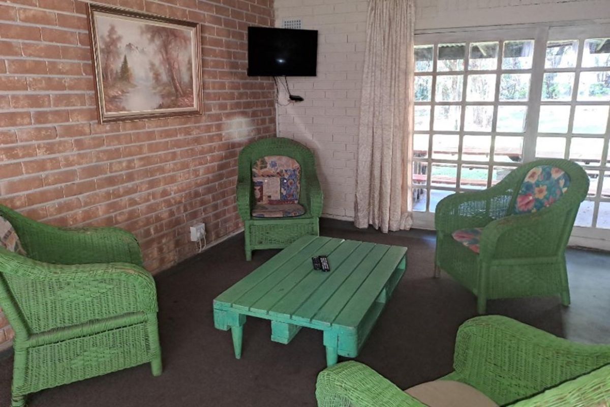 A living room featuring exposed and painted brick walls, carpeted flooring, and large french doors providing natural light and access to the outdoors.