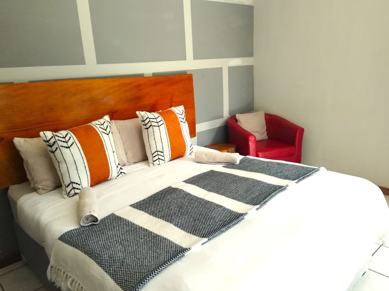 A bedroom featuring a wooden headboard and a decorative grey and white panelled feature wall.