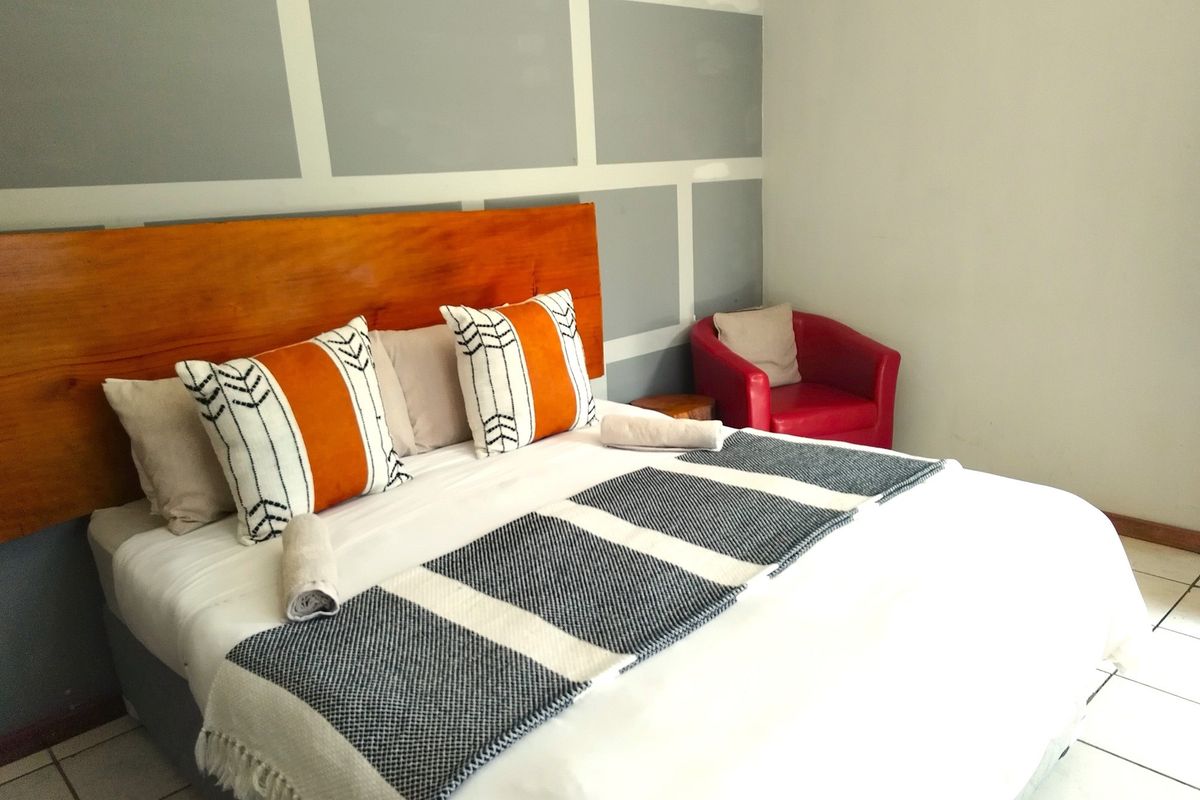 A bedroom featuring a wooden headboard and a decorative grey and white panelled feature wall.