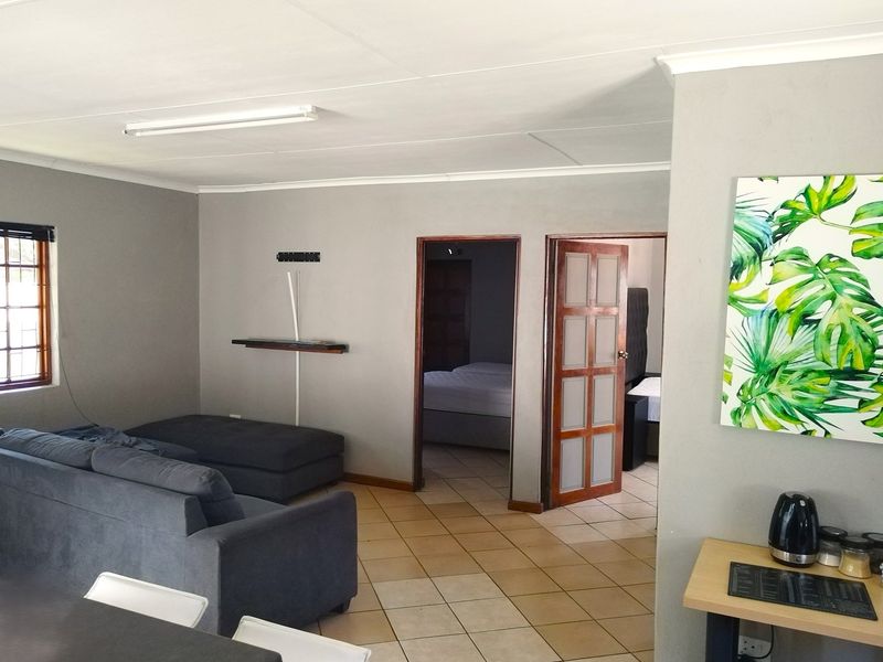 Open plan living area featuring tiled flooring, neutral wall tones, and direct access to adjacent bedroom spaces.