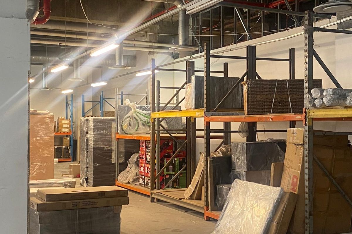 Industrial retail storage space featuring high ceilings with exposed ductwork and heavy-duty metal racking systems for efficient inventory management.