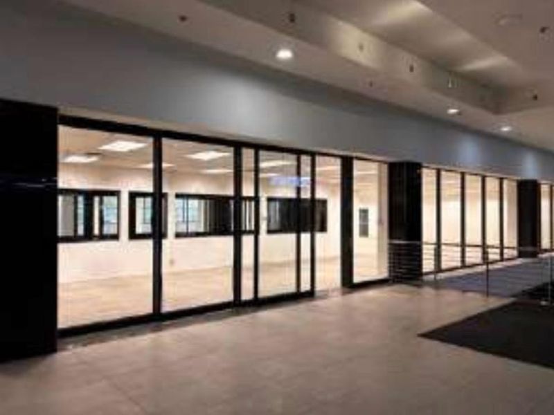 Spacious open-plan retail unit featuring a modern glass storefront, recessed lighting, and neutral tiled flooring, suitable for various commercial business applications.