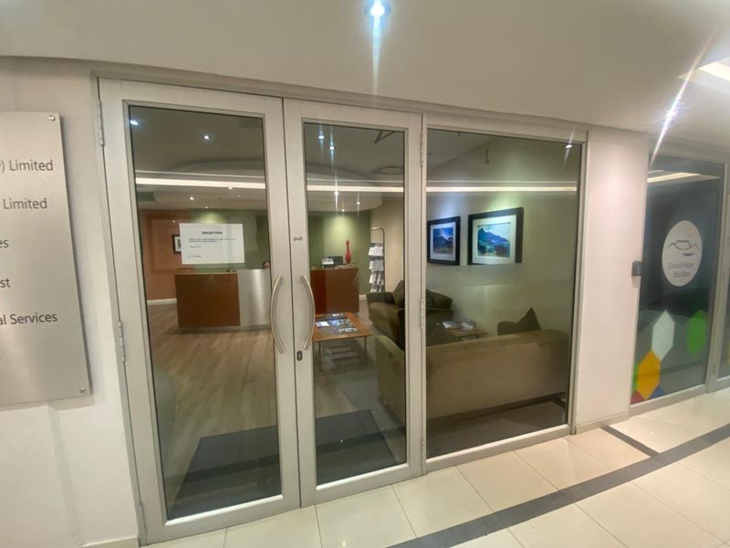 Professional office entrance featuring glass double doors, recessed lighting, and clear signage, leading into a reception and waiting area.