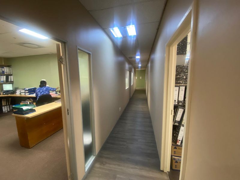 A functional office hallway featuring laminate flooring, recessed lighting, and access to adjacent office spaces.