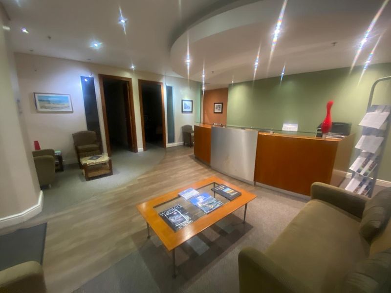 Professional office reception area featuring a built-in reception desk, recessed lighting, and a modern dropped ceiling design.