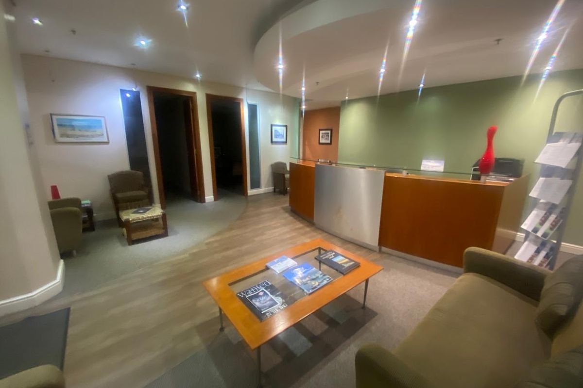 Professional office reception area featuring a built-in reception desk, recessed lighting, and a modern dropped ceiling design.